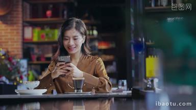 咖啡厅内边喝咖啡边使用手机的青年女人